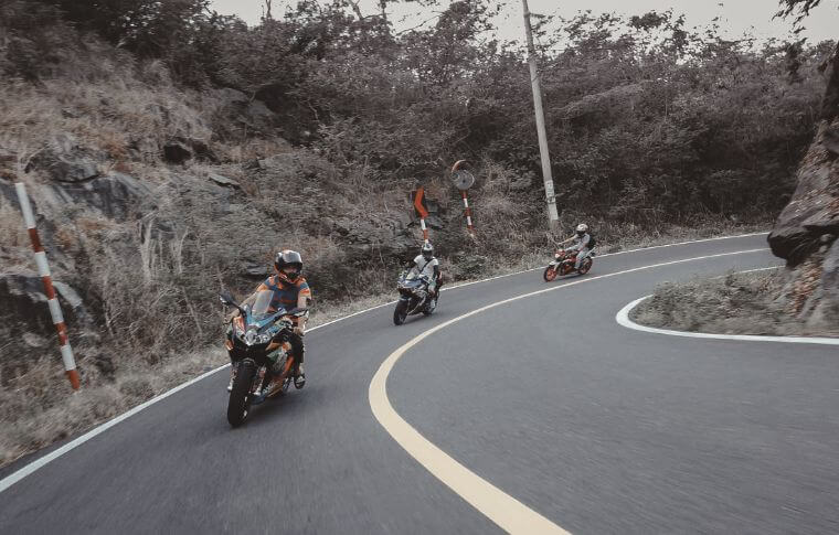 Three riders leaning into a mountain curve.
