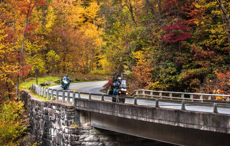 Motorcyclists completing a bend in the Smoky Mountains with a back drop of fall foliage
